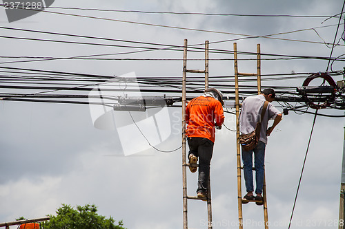 Image of lineman working on cable - telephone pole from ladder