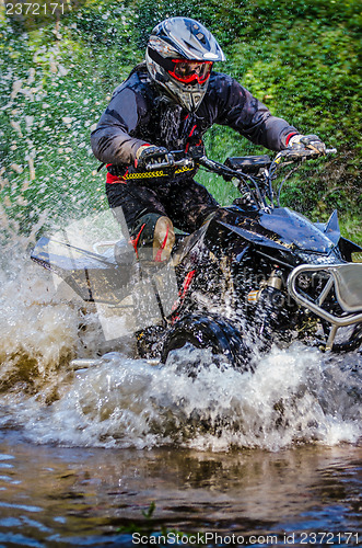 Image of Quad rider through water stream