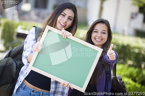 Image of Mixed Race Female Students with Thumbs Up Holding Blank Chalkboa
