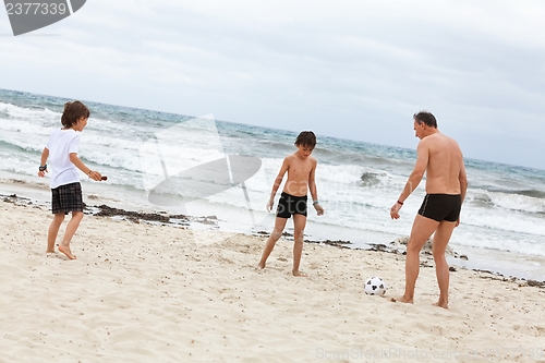 Image of happy family father two kids playing football on beach summer 