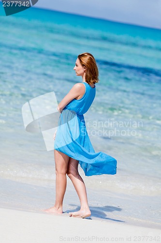 Image of beautiful woman in blue dress on beach in summer