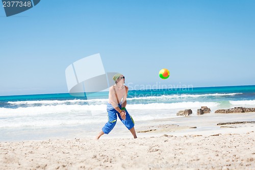 Image of attractive young man playing volleyball on the beach