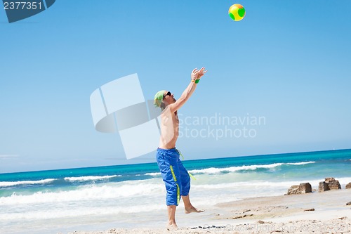 Image of attractive young man playing volleyball on the beach