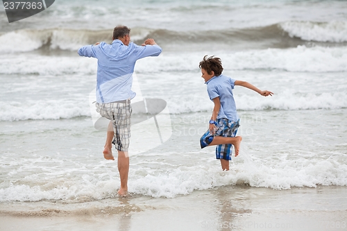 Image of father and sons on the beach playing in the sand