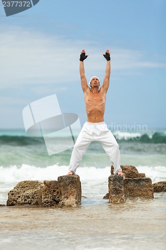 Image of healthy man doing pilates yoga meditation on beach summer