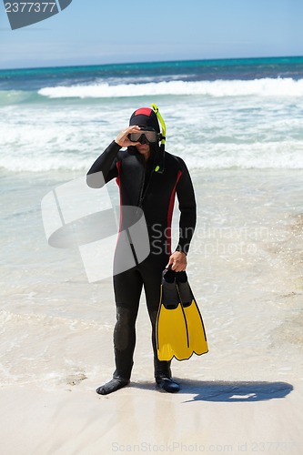 Image of male diver with diving suit snorkel mask fins on the beach