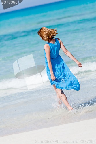 Image of beautiful woman in blue dress on beach in summer