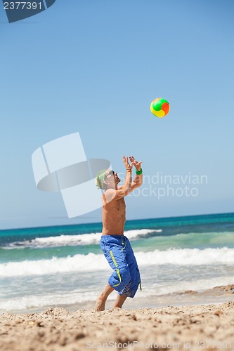 Image of attractive young man playing volleyball on the beach