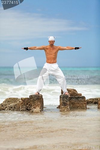 Image of healthy man doing pilates yoga meditation on beach summer