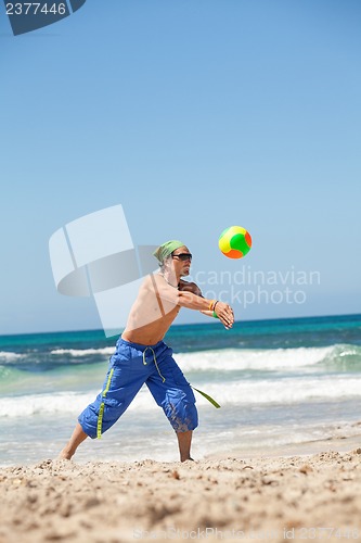 Image of attractive young man playing volleyball on the beach