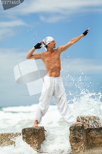 Image of healthy man doing pilates yoga meditation on beach summer