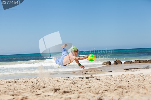 Image of attractive young man playing volleyball on the beach