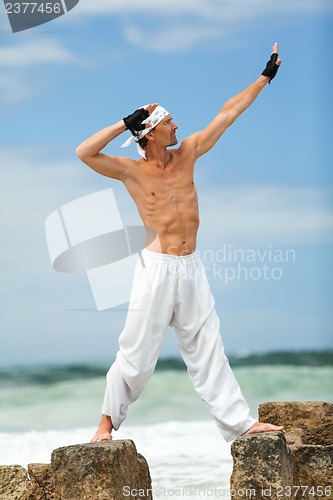 Image of healthy man doing pilates yoga meditation on beach summer