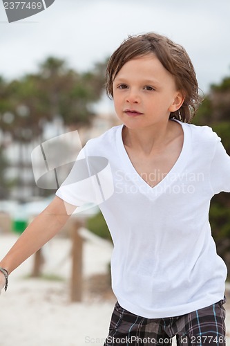 Image of cute little boy playing in sand on beach in summer