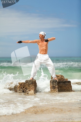 Image of healthy man doing pilates yoga meditation on beach summer