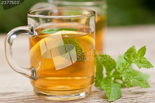 Image of fresh tasty hot tea lemon and mint outdoor in summer 