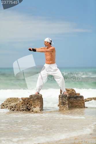 Image of healthy man doing pilates yoga meditation on beach summer