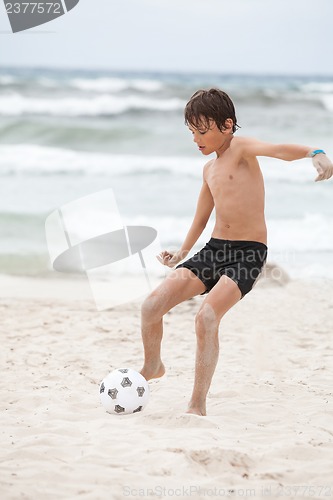 Image of happy little boy  playing football on beach summer 