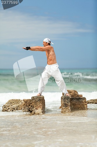 Image of healthy man doing pilates yoga meditation on beach summer