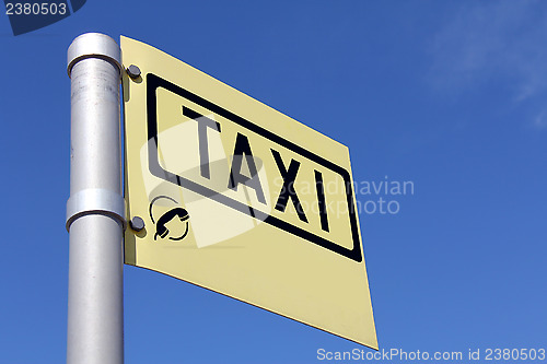 Image of Yellow Taxi Sign against Blue Sky