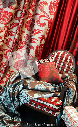 Image of Luxurious red chair with satin pillows and curtains