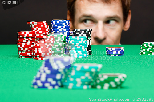 Image of man looking under the table on playing chips