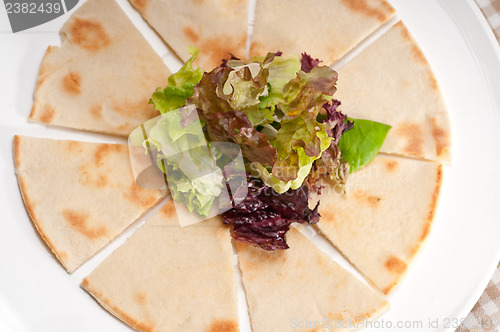 Image of garlic pita bread pizza with salad on top