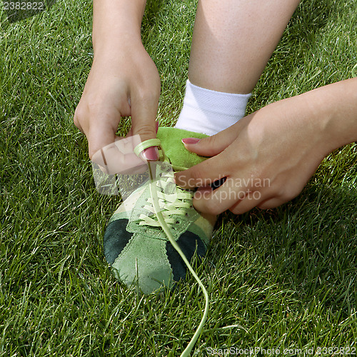 Image of girl ties laces on shoes