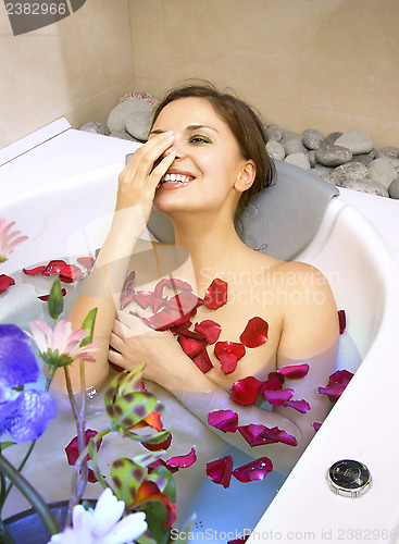 Image of happy woman in a bath with rose-petals