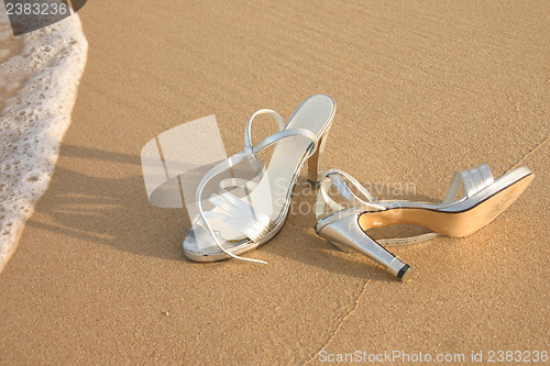 Image of Ladies silver shoes on  a beach