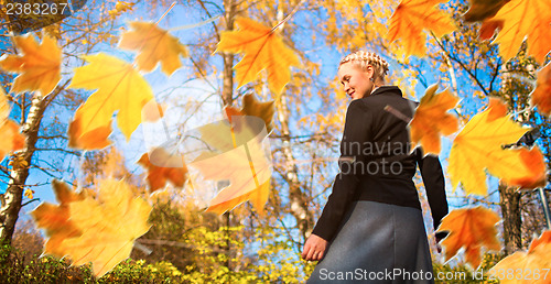 Image of Woman and autumn leaves in the park.