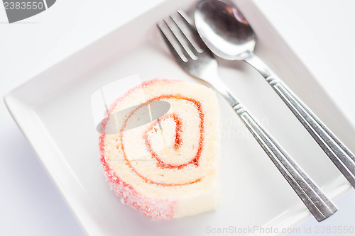 Image of Strawberry jam roll cake with spoon and fork