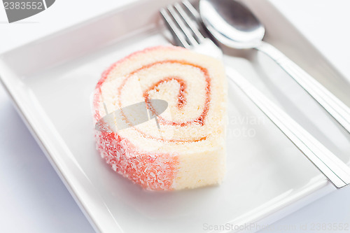 Image of Pink jam roll cake with spoon and fork