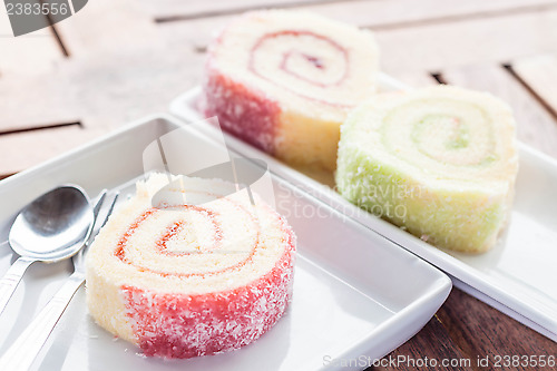 Image of Colorful jam rolls on white dish with spoon and fork