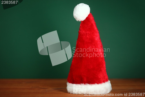 Image of Red Santa Hat With Copy Space on Green and Wood Background