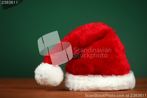 Image of Red Santa Hat With Copy Space on Green and Wood Background