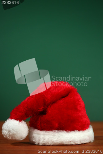 Image of Red Santa Hat With Copy Space on Green and Wood Background