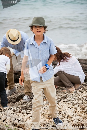 Image of happy family sitting on rock and watching the ocean waves