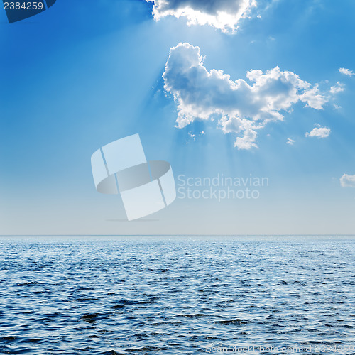 Image of blue sea and cloudy sky with sun over it