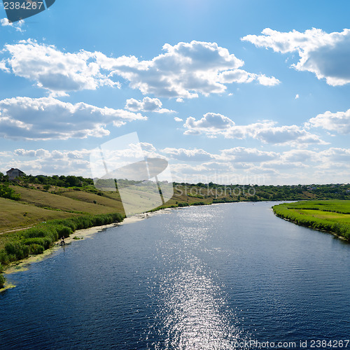 Image of view to river with reflections and blue cloudy sky