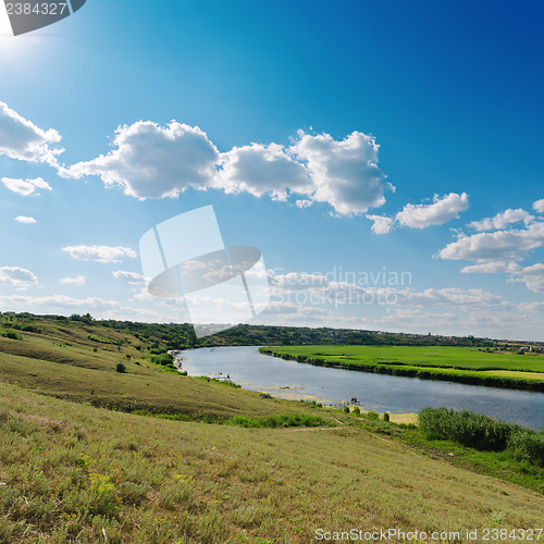 Image of cloudy sky with sun over river