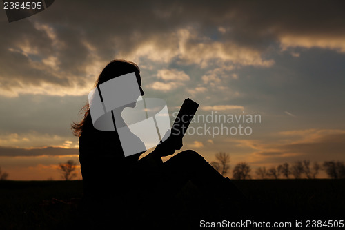 Image of Teen girl reading book outdoors