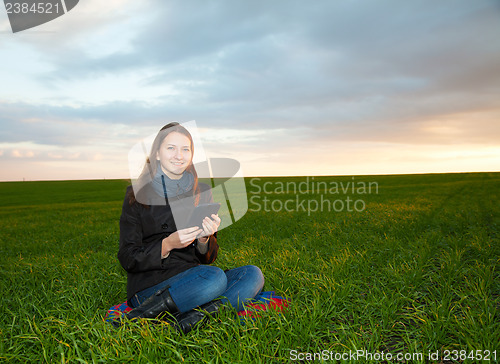 Image of Teen girl reading electronic book outdoors