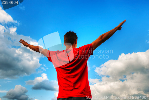 Image of Young man staying with raised hands