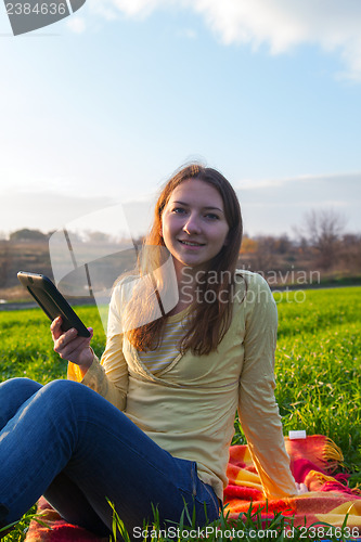 Image of Teen girl reading electronic book outdoors