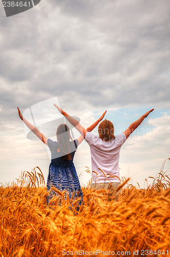 Image of Couple staying with raised hands at a wheat field