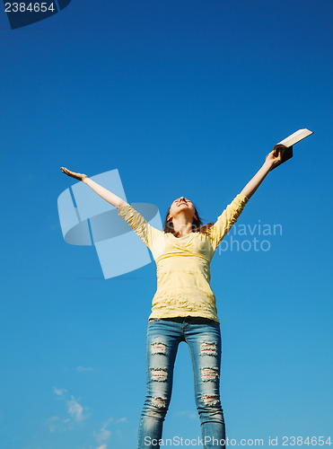 Image of Young woman staying with raised hands
