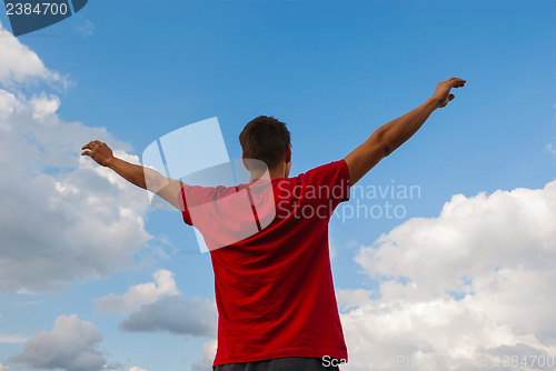 Image of Young man staying with raised hands