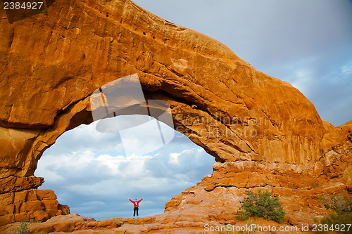 Image of Woman staying with raised hands inside an Arch