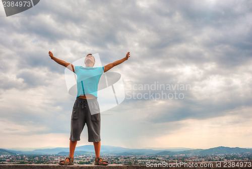 Image of Young man staying with raised hands